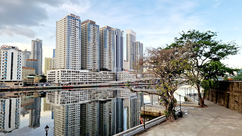 The skyline along the Pasig River. The skyscrapers are reflected in the water.