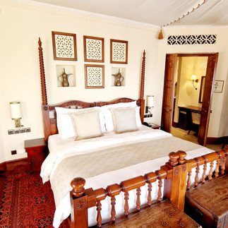 A massive king-size bed, with niches on the wall above containing old Arabic coffee pots.