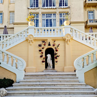 Links und Rechsts führen zwei klassische Treppen vom Garten ins Hotel. In der Mitte steht eine antike, kopflose Figur.