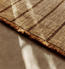Athens Stripes Rug by Ferm Living - Close-up of a woven, brown rug with sunlight on a concrete floor. Mood board from design accessories by Kachi Interiors luxury interior design studio London