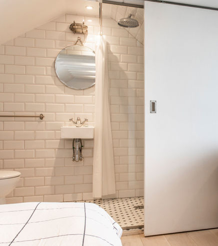Bathroom with white subway tiles, round mirror, and shower space. Kachi Interiors.