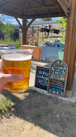 Hand holding beer in plastic cup near chalkboard sign with text.