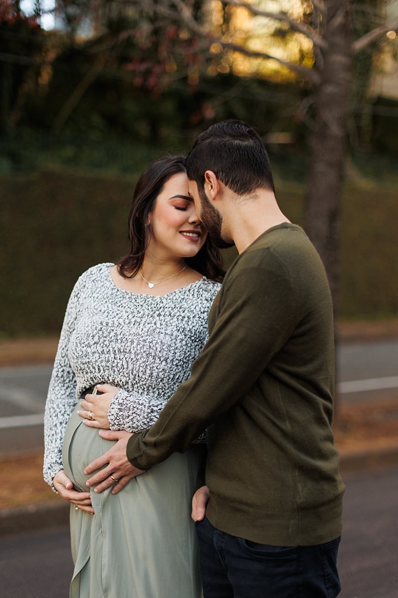 Casal ao pôr do sol posando para ensaio fotográfico de gestante