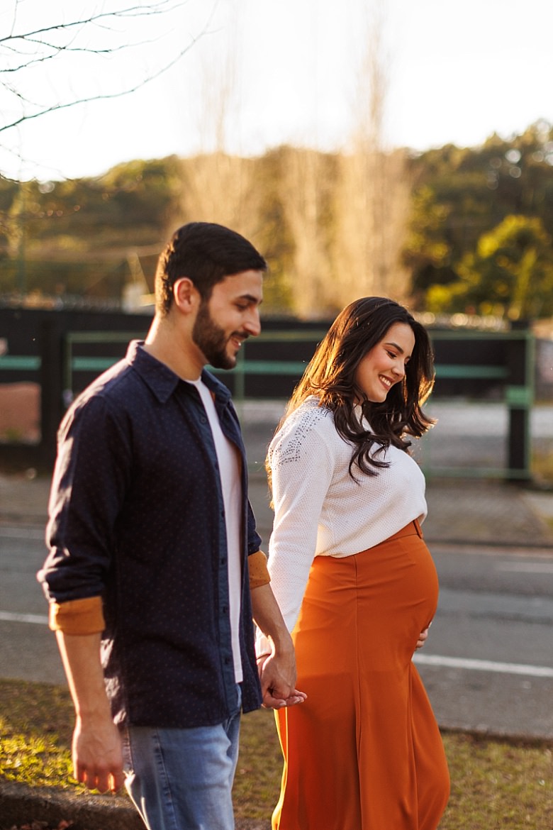 Casal ao pôr do sol posando para ensaio fotográfico de gestante