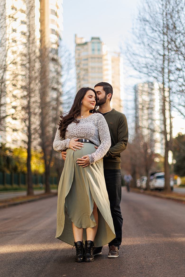 Casal ao pôr do sol posando para ensaio fotográfico de gestante