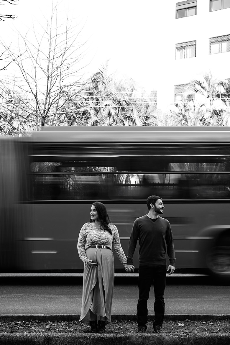 Casal ao pôr do sol posando para ensaio fotográfico de gestante