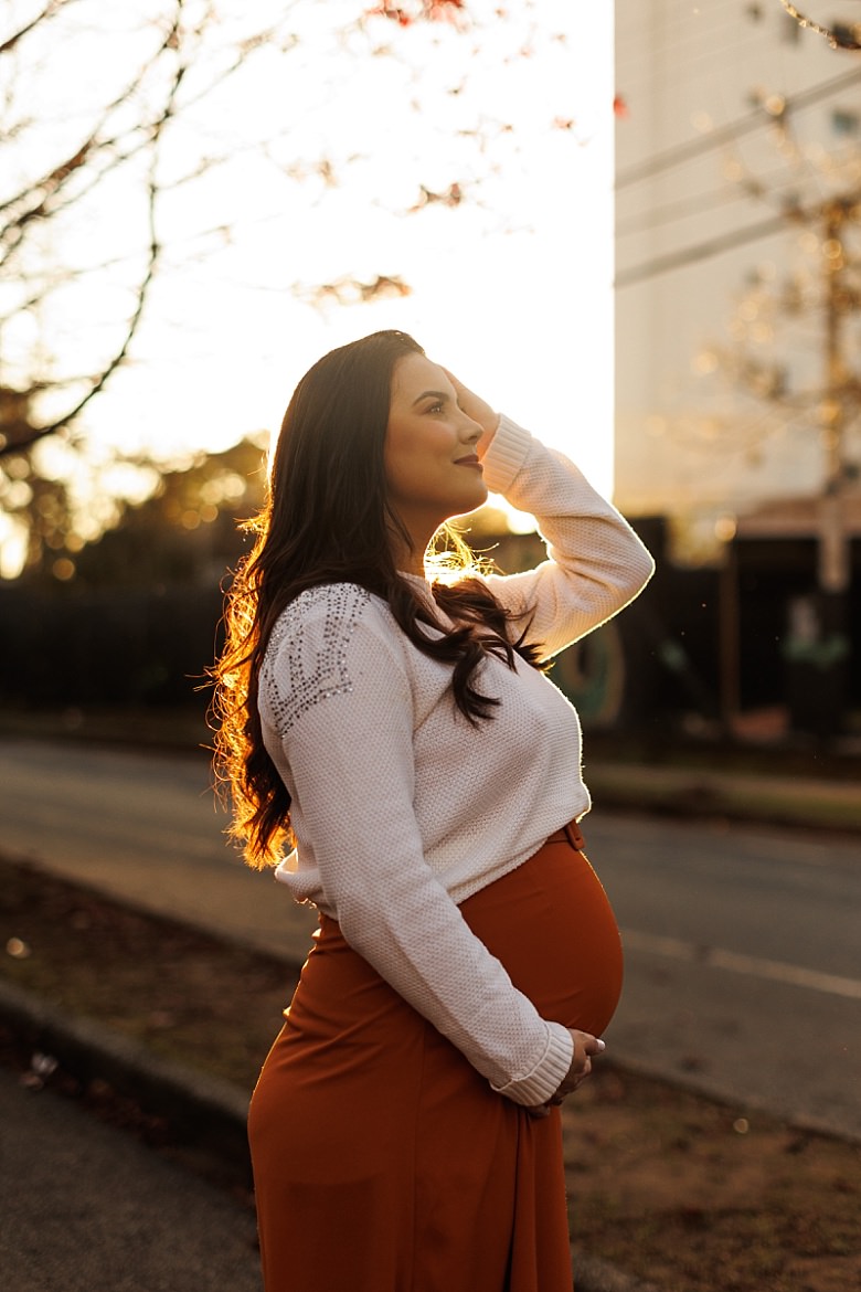 Gestante ao pôr do sol posando para ensaio fotográfico de gestante