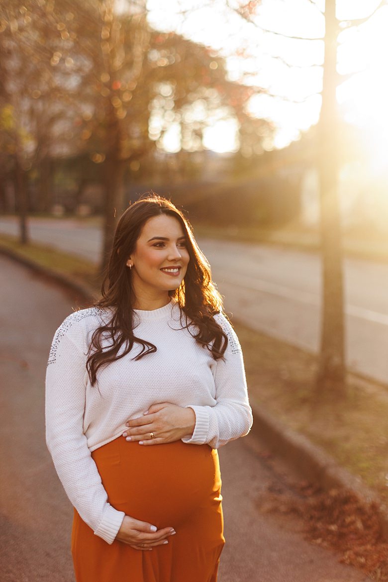 Gestante ao pôr do sol posando para ensaio fotográfico de gestante