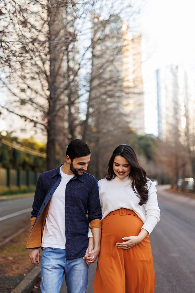 Casal ao pôr do sol posando para ensaio fotográfico de gestante