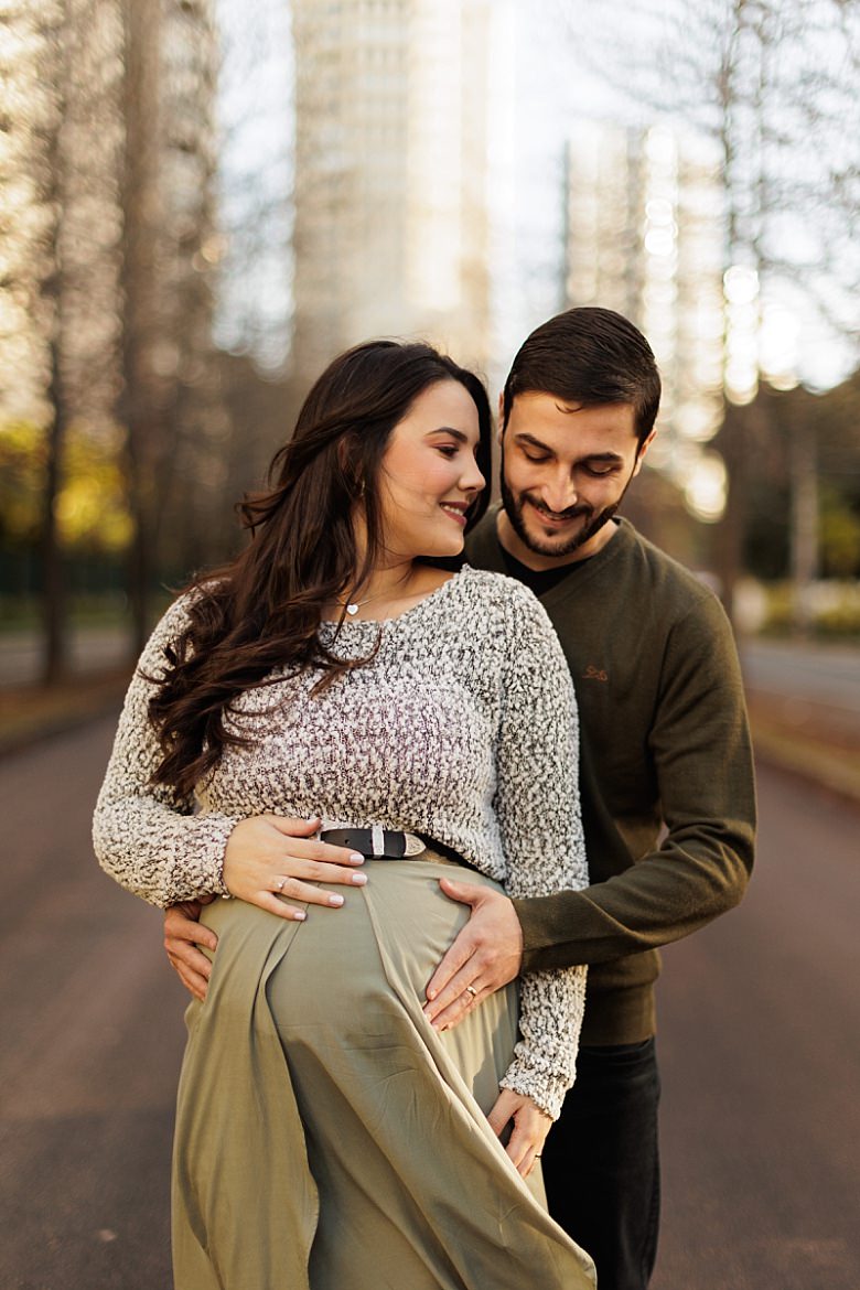 Casal ao pôr do sol posando para ensaio fotográfico de gestante