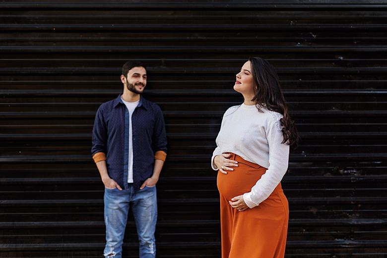 Casal ao pôr do sol posando para ensaio fotográfico de gestante