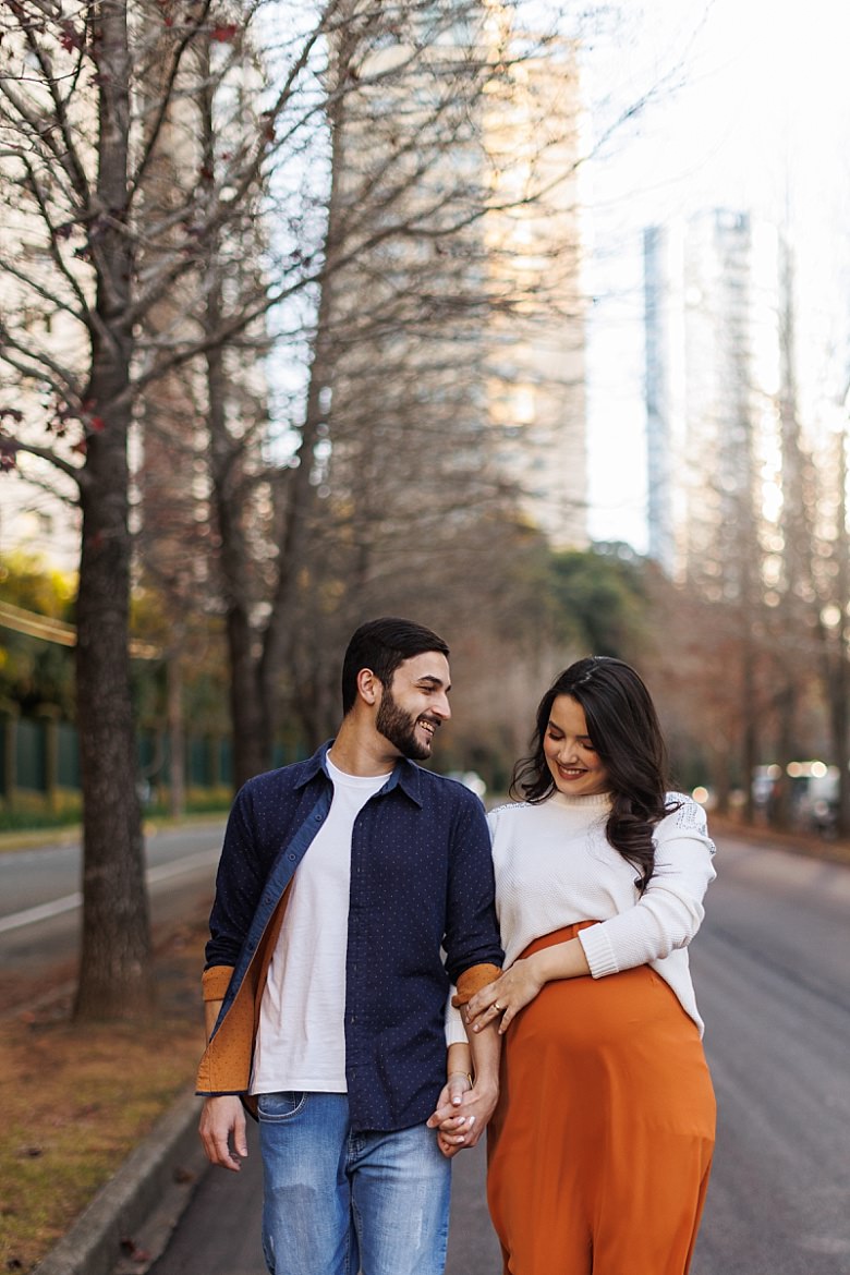 Casal ao pôr do sol posando para ensaio fotográfico de gestante