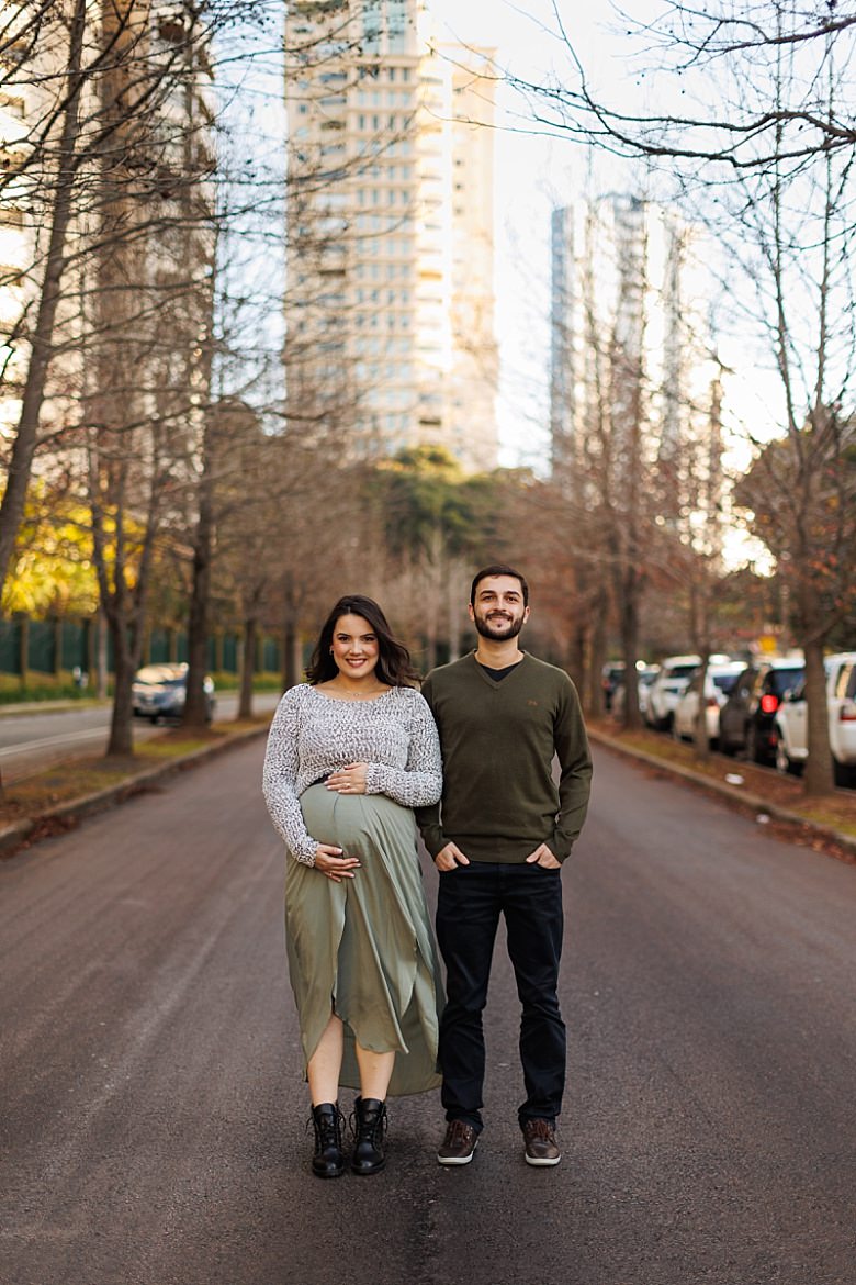 Casal ao pôr do sol posando para ensaio fotográfico de gestante
