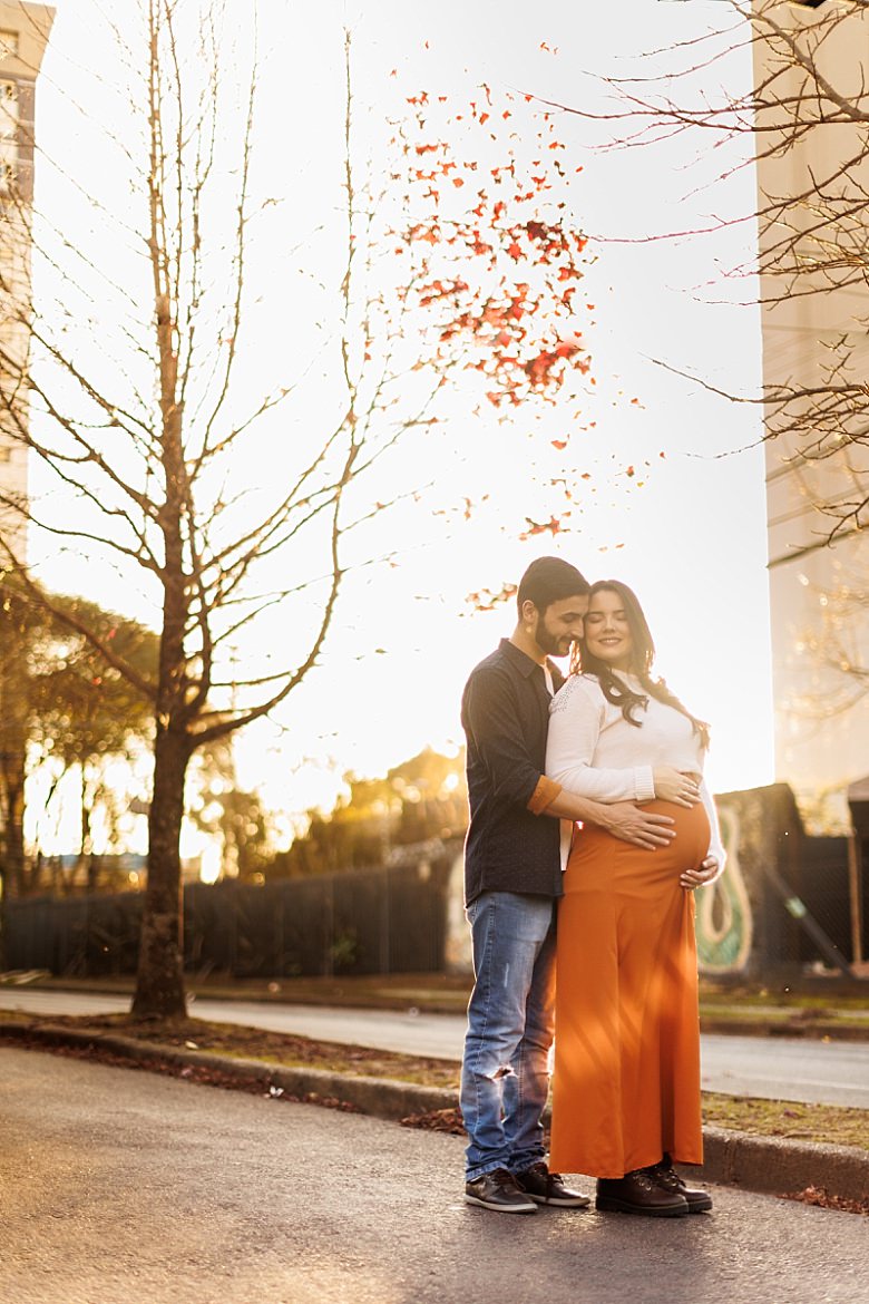 Casal ao pôr do sol posando para ensaio fotográfico de gestante