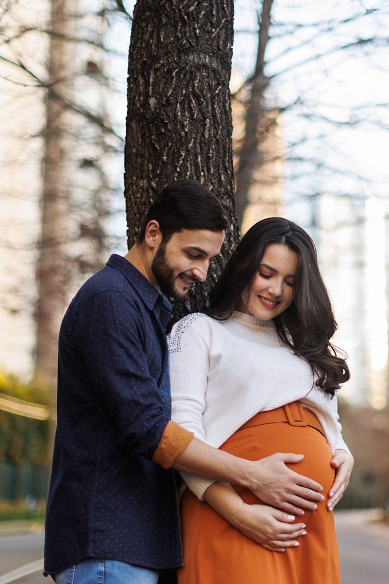 Casal ao pôr do sol posando para ensaio fotográfico de gestante