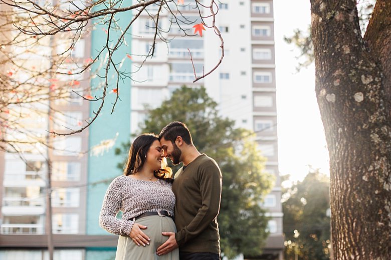 Casal ao pôr do sol posando para ensaio fotográfico de gestante
