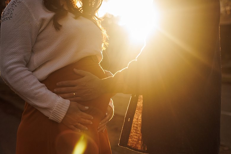 Casal ao pôr do sol posando para ensaio fotográfico de gestanteEnsaio fotográfico de gestante realizado ao pôr do sol na cidade de Curitina no Paraná.