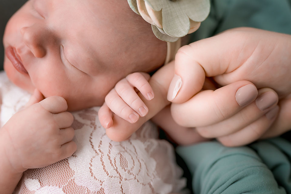 newborn infant holding parents finger