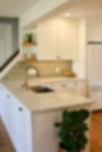 White kitchen island with farmhouse sink and sage green tile backsplash
