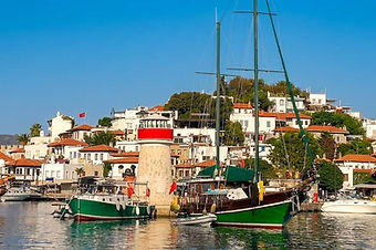 Panoramic view of Marmaris harbor featuring the iconic lighthouse, a vibrant waterfront, and luxury Gulets at anchor.
