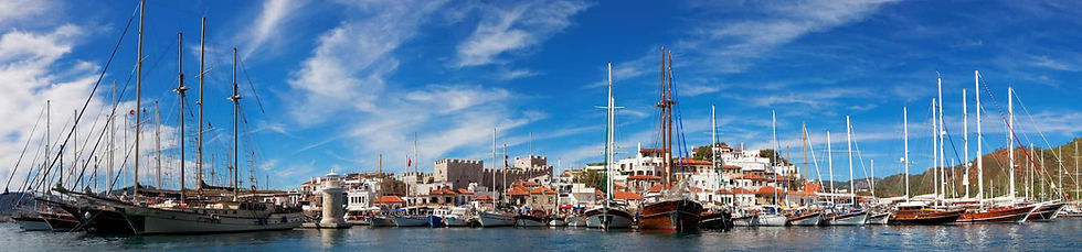 Panoramic view of Marmaris harbor, the castle, the vibrant waterfront, and luxury Gulets at anchor.