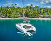 Luxury catamaran at anchor along a palm-fringed white sand beach in French Polynesia during a premium bareboat yacht charter.