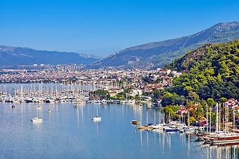 Panoramic view over the bustling harbor of Fethiye, Turkey, featuring a magnificent lineup of luxury Gulets and motorsailers at the waterfront.