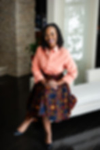 Smiling woman in a peach shirt and colorful patterned skirt