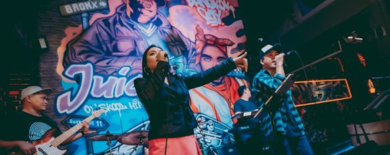 Live music on a Thailand pub crawl – a man playing guitar, entertaining pub crawlers at a lively Bangkok bar.