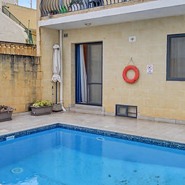 🏡 SANNAT, GOZO
Private Two-Bedroom Residence with Pool
Ref: 26-0034 | Long Let | Gozo Direct
In a peaceful residential enclave of Sannat, this elegant two-bedroom ground-floor residence offers the rare luxury of a private swimming pool, refined contemporary interiors, and exceptional privacy — a distinctive long-let opportunity in one of Gozo’s most desirable villages.
Designed for comfortable year-round living, the property blends modern finishes with traditional limestone character, creating a warm yet sophisticated aesthetic throughout.
The Residence
Upon entering, one is welcomed into a bright open-plan living and dining area framed by classic Maltese stone walls and soft neutral tones. The space flows effortlessly into a fully fitted contemporary kitchen featuring integrated appliances, gas hob, oven, extractor hood and generous cabinetry — ideal for both daily living and entertaining.
Large glass doors open directly onto the private outdoor terrace and pool area, creating seamless indoor-outdoor living.
Outdoor Living
The private swimming pool is the centrepiece of the residence — a tranquil courtyard setting perfect for relaxation, morning swims or intimate evening gatherings.
Low-maintenance tiling and surrounding terrace space provide practicality while maintaining an understated elegance.
A rare find for a long-term rental in Sannat.
Accommodation
• Two double bedrooms with natural light
• Master bedroom with warm neutral styling
• Guest bedroom with bold accent finishes
• Modern main bathroom
• Additional bathroom facilities
• Fully furnished and ready for immediate occupation
Each bedroom is thoughtfully presented, offering a calm retreat atmosphere suitable for professionals or a couple seeking refined island living.
Additional Features
• Private swimming pool
• Fully equipped modern kitchen
• Air-conditioning
• Contemporary furnishings
• Quiet residential location
• Excellent indoor-outdoor flow
Location
Sannat remains one of Gozo’s most sought-after villages — appreciated for its peaceful environment, proximity to Ta’ Ċenċ cliffs, and convenient access to Victoria and Mgarr Harbour.
This residence offers the privacy of village living while remaining connected to all island amenities.