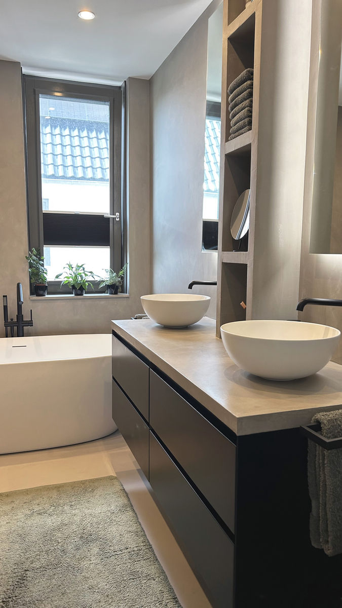 Badkamer met stijlvolle ronde wastafels en betonciré afwerking – ontwerp door De Interieurontwerpers Stefanie Lamers