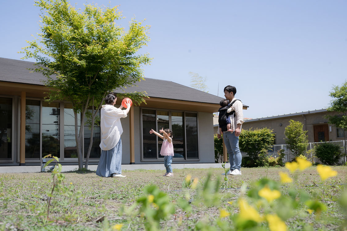 子育て世代家族が、平屋の庭でボール遊びをしている