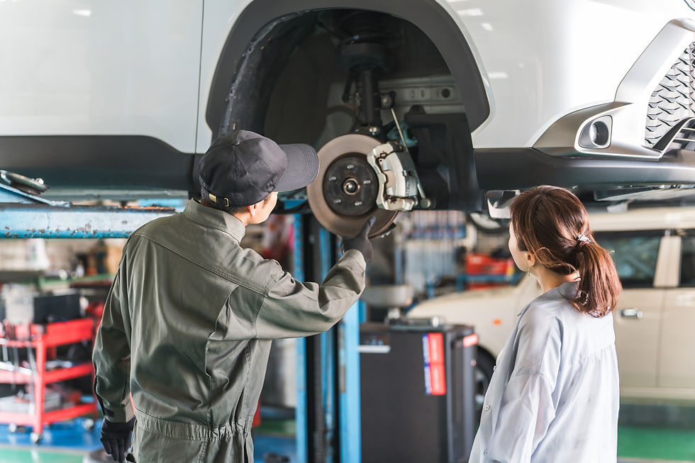 車検でリフトアップされた車の説明を受ける日本人女性客と整備士の男性スタッフ