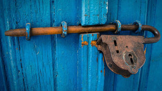 Eine blau gestrichene Holztür mit Riegel und Vorhängeschloss