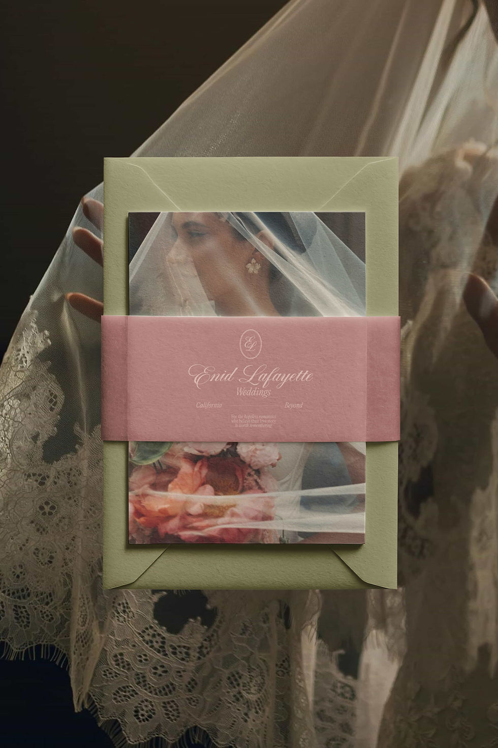 A wedding invitation suite is presented with a bridal veil draped over it. The invitation features images of a bride and a floral bouquet.