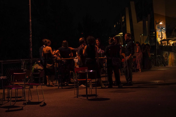 Tische und Sesseln stehen vor Lillis Stadtbahnbögen und Menschen stehen dazwischen und unterhalten sich.