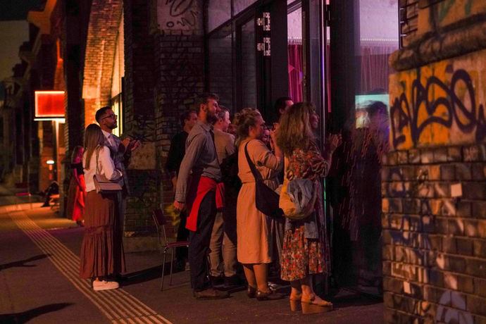 Einige Gäste schauen von außen durch die Scheiben bei etwas drinnen zu.