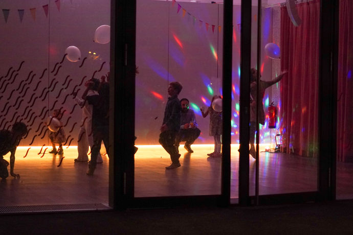 Foto von außen, Kinder tanzen mit Discolichtern im Studio.