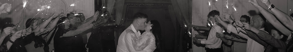 Couple has their final kiss on their wedding day in front of a barn with people standing all around holding sparklers