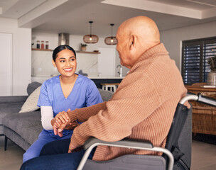 Caregiver and elderly man in a wheelchair holding hands and smiling.