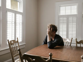 Man sitting at table holding his head