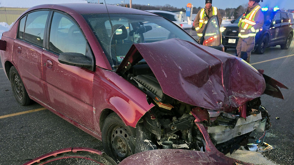 Crashed maroon car with front damage on road. Two emergency responders in yellow vests and a police car with blue lights in the background.