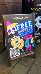 Free churros when you download the my iguanas app. The design features a skeleton in a sombrero, playing guitar, and some brightly coloured churros sprinkled in the bottom right, with a QR code in the bottom left