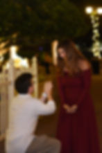 Close-up view of a sparkling engagement ring held near the glowing Christmas tree lights