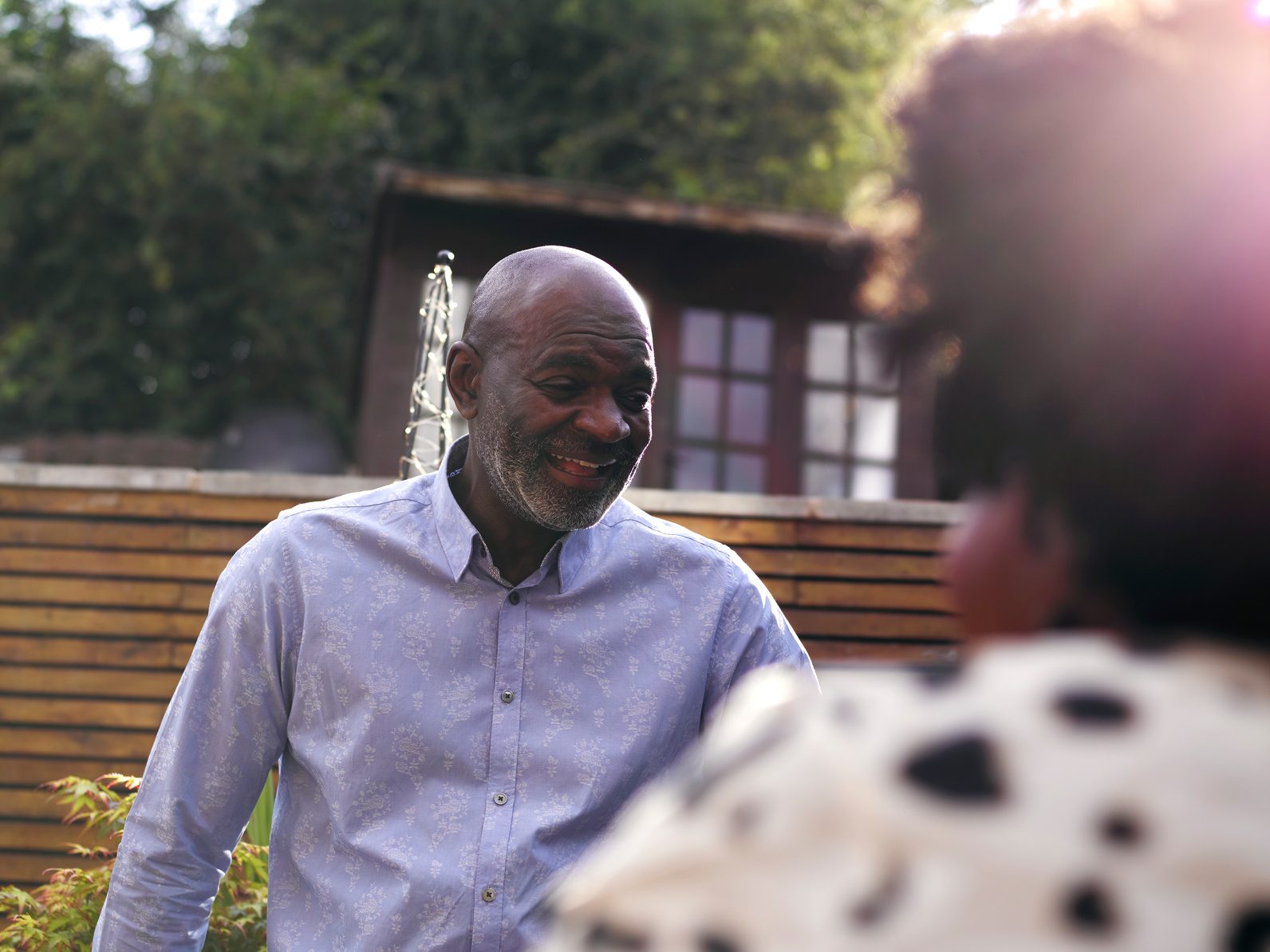 A smiling older man talking with a woman outdoors