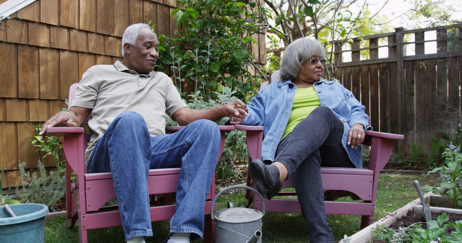 An older Black couple relaxing together in their backyard garden