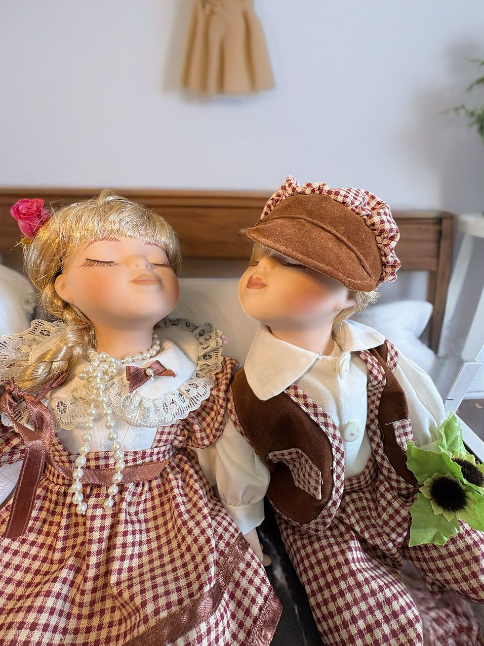 Vintage style boy and girl kissing doll pair in burgundy gingham outfits with cream accents, seated side by side