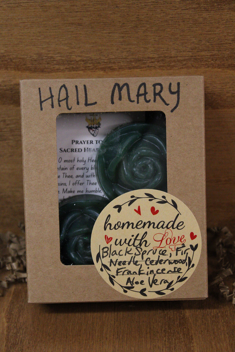 Thumbnail: Packed dark green Catholic soap that are rose-shaped and propped against a wooden background.