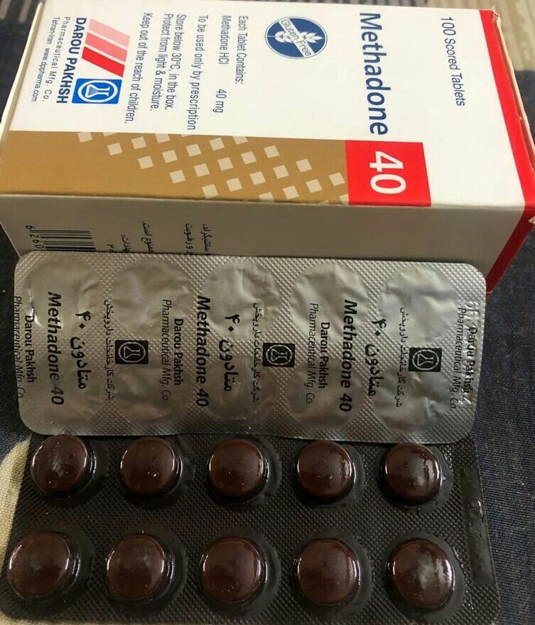 Box and blister pack of Methadone 40 tablets. Text displays dosage and manufacturer. Pills are dark brown. Background is a dark surface.