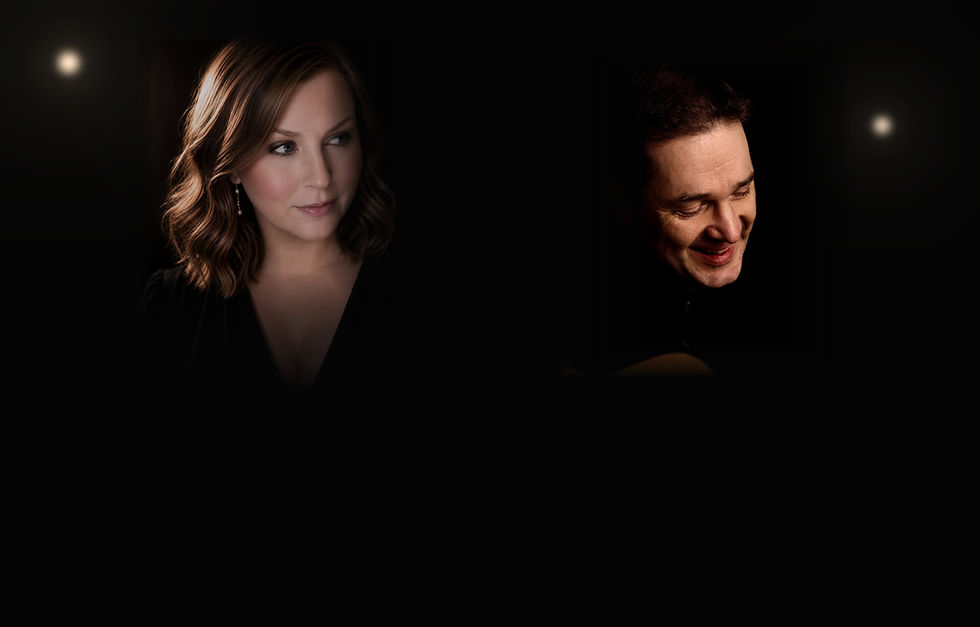 Dark studio portrait of a woman and smiling man lit by soft spotlights, with a guitar edge visible.